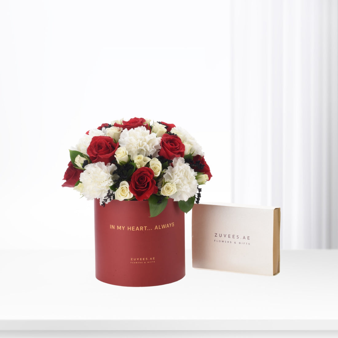 Red and white roses in elegant red hat box with gold text.