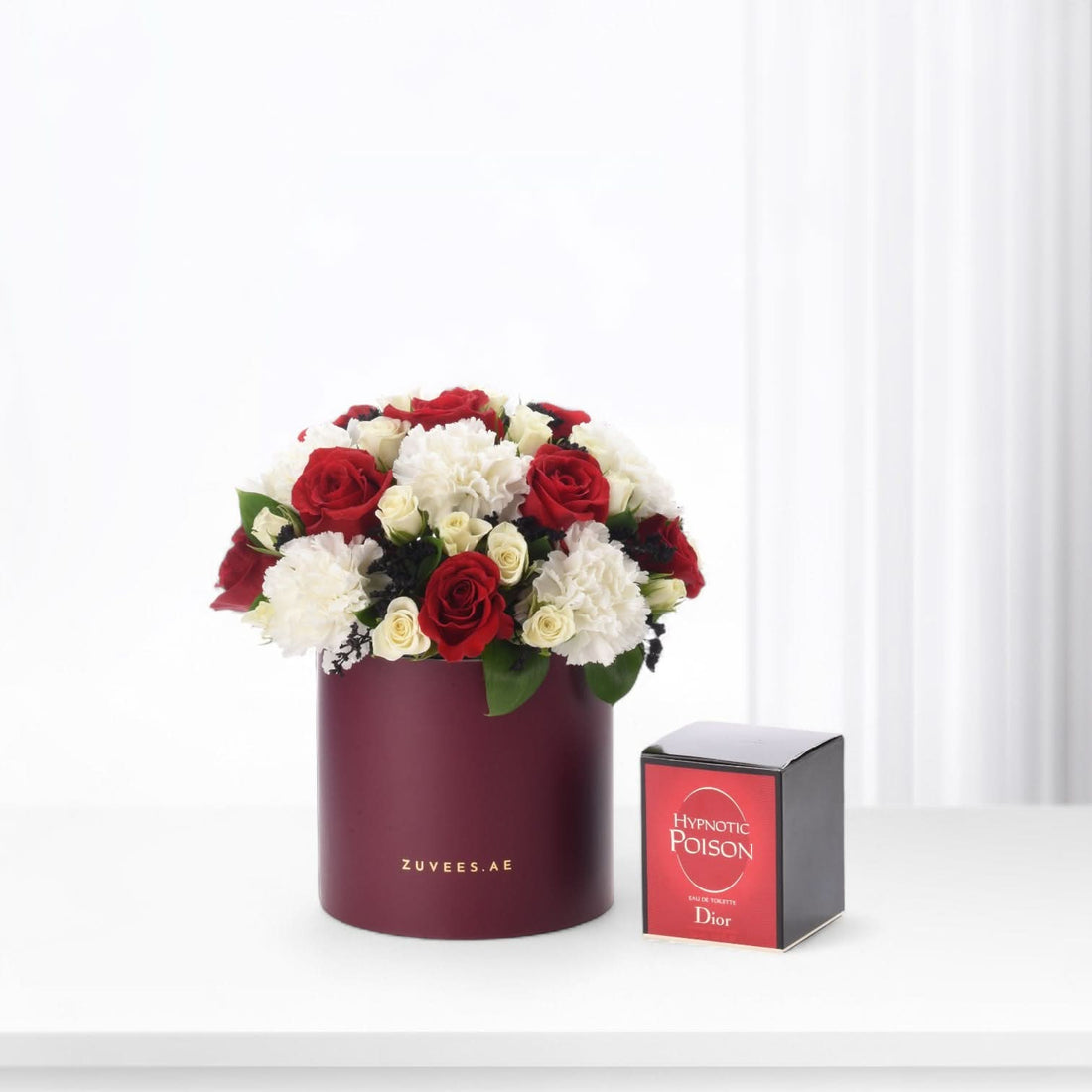 Luxurious red and white roses in burgundy cylinder, paired with Dior Hypnotic Poison perfume.