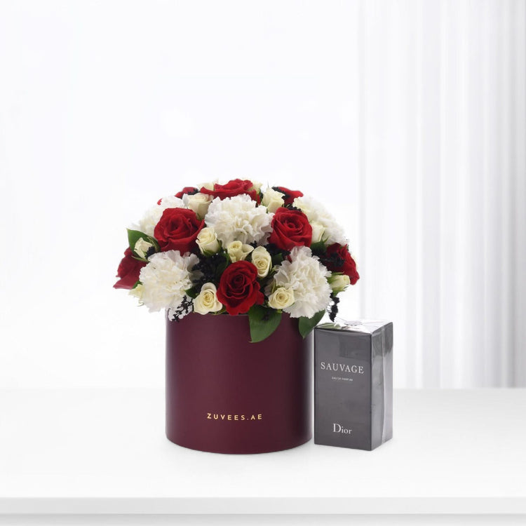 Elegant red and white roses in burgundy hat box beside Dior Sauvage perfume.