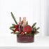 Elegant burgundy holiday gift basket with champagne, cake, and festive greenery.