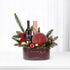 Elegant burgundy holiday gift basket with festive greenery, red roses, and branded treats.