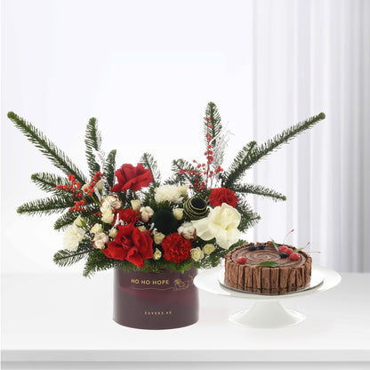 Festive red, white, green floral arrangement with pine, berries, and chocolate Yule log cake.