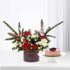 Elegant red and white floral arrangement with pine, berries, and cake on white stand.