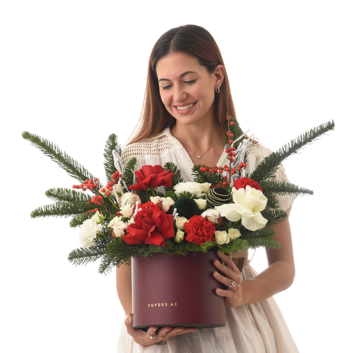 Woman smiles holding festive red and white floral arrangement in burgundy box.