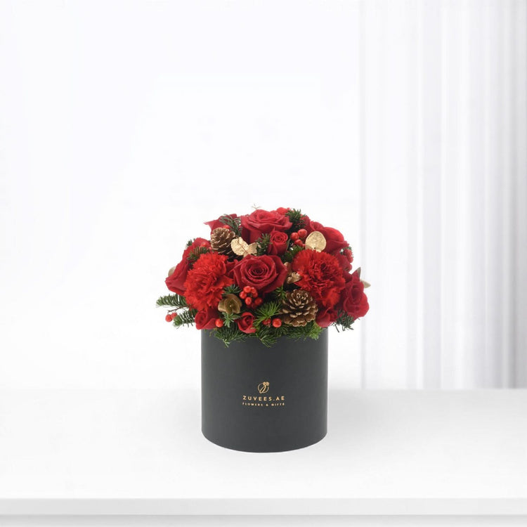 Vibrant red roses and carnations in sleek black box with gold accents.