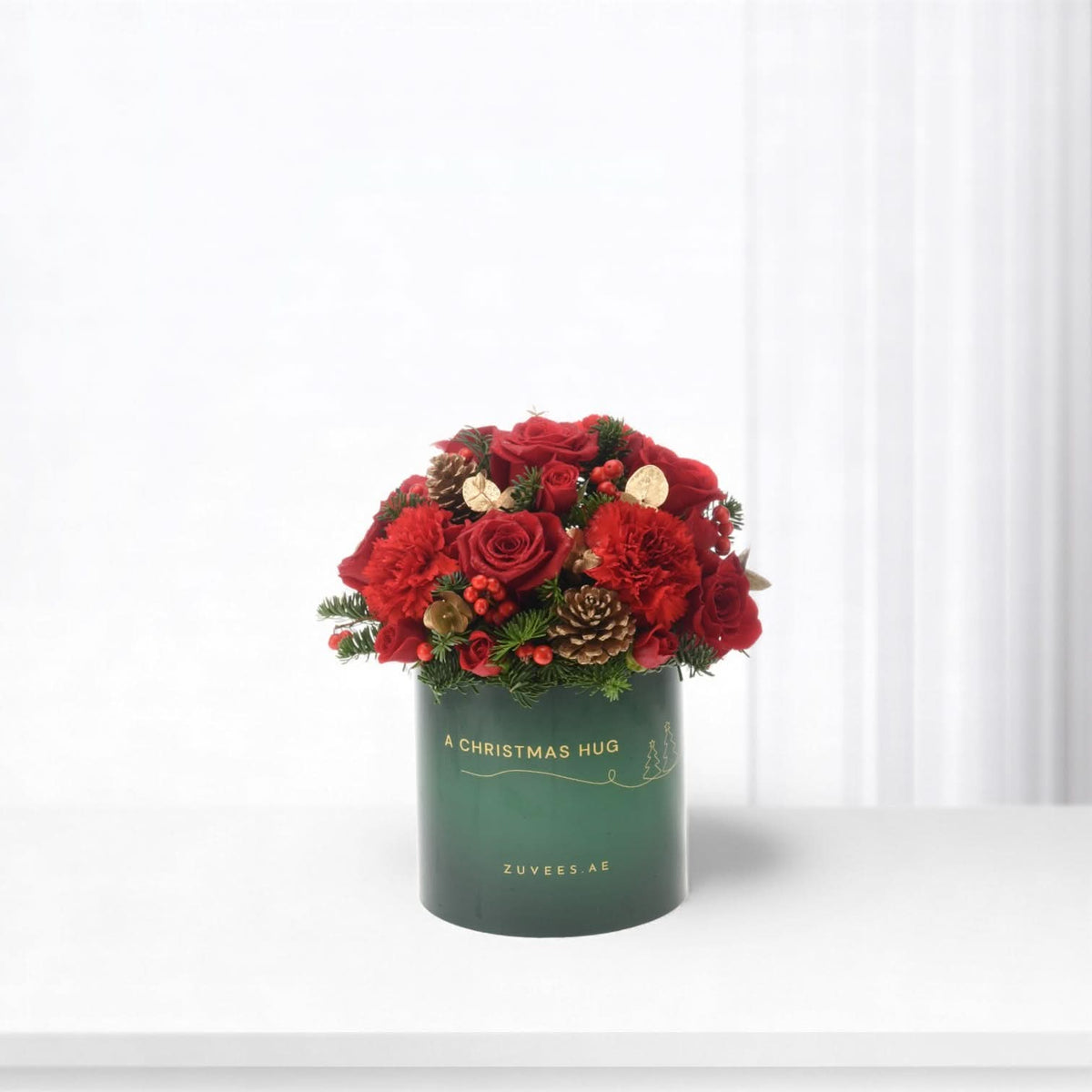 Vibrant red roses and berries in festive green box labeled "A Christmas Hug".