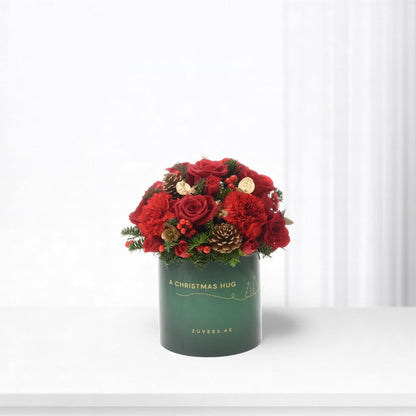 Vibrant red roses and berries in festive green box labeled "A Christmas Hug".