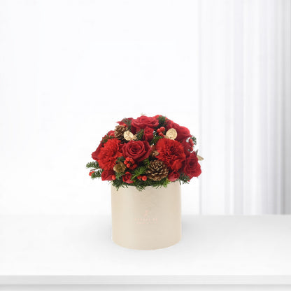 Vibrant red roses and carnations in beige box with pinecones and berries.