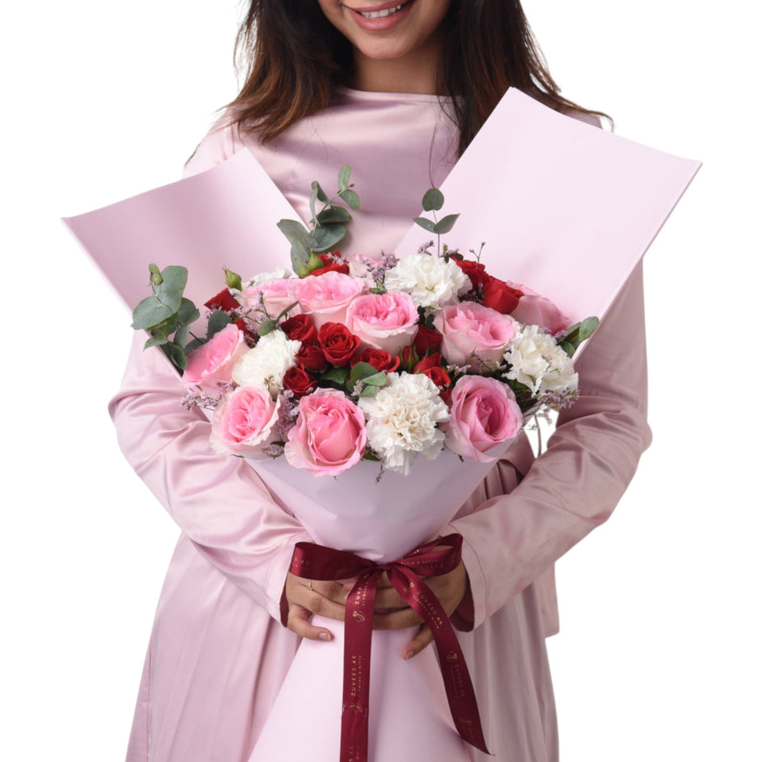 Pink-wrapped bouquet with red, pink, and white roses, tied with burgundy ribbon.