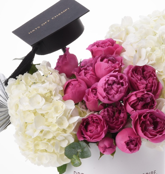 Vibrant magenta roses and white hydrangeas crowned with "Hats Off Champ!" graduation cap.