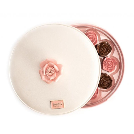Elegant rose-shaped chocolates in blush pink and dark brown, nestled in a soft cream lid adorned with a matching rose and "Bostani" label.