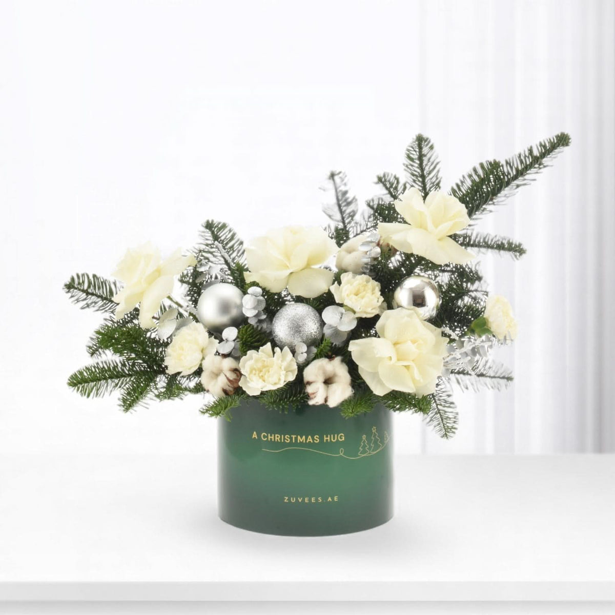 Elegant white roses, silver ornaments, pine in green "Christmas Hug" vase, minimalist holiday centerpiece.