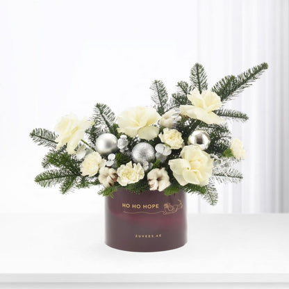 Elegant white floral arrangement with silver ornaments in burgundy holiday box.
