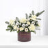 Elegant white floral arrangement with silver ornaments in burgundy holiday box.