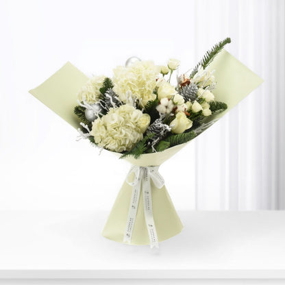 Elegant winter bouquet: white hydrangeas, roses, frosted pine, silver ornaments, pale green wrap, branded ribbon.