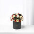 Elegant black box holds red and white roses, cotton, pinecones, and gold ornaments.