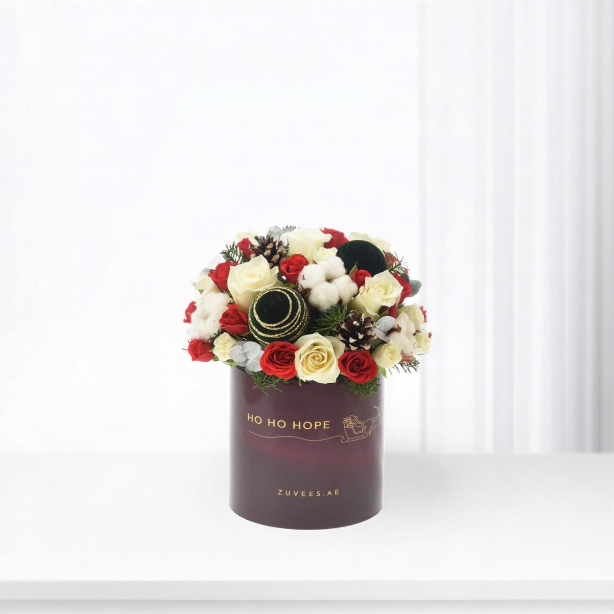 Elegant holiday floral arrangement in burgundy box with "Ho Ho Hope" text.