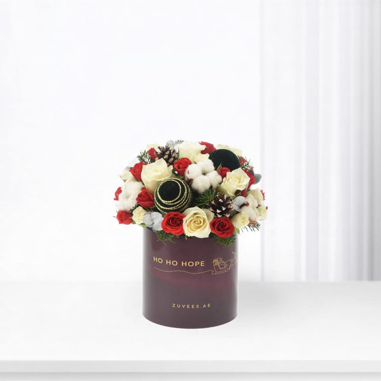Elegant holiday floral arrangement in burgundy box with "Ho Ho Hope" text.