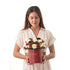 Woman holds festive red box bouquet with red/white roses, pinecones, and "Elf-Approved" text.