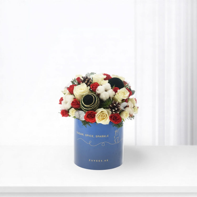 Festive red and white roses with pinecones, cotton, gold ornaments in blue "Sugar, Spice, Sparkle" box.