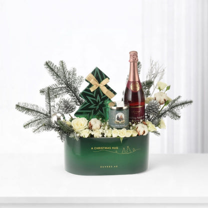 Elegant green Christmas gift basket with champagne, candle, and festive florals.