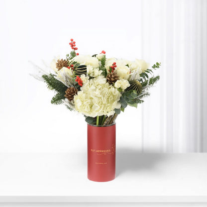 White roses and hydrangeas in festive red vase with pinecones and berries.