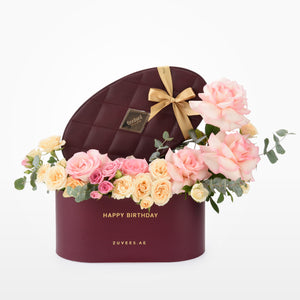 Luxury burgundy box with pink, peach roses, eucalyptus, gold ribbon, and "Happy Birthday" inscription.