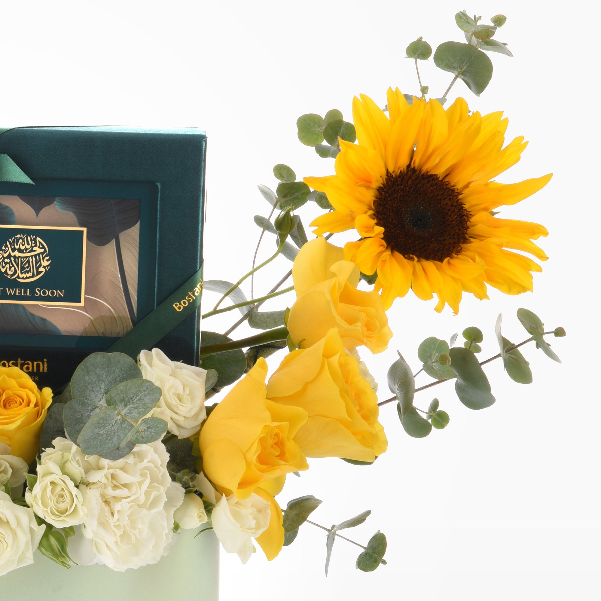 Vibrant sunflower, yellow and white roses with eucalyptus, beside teal "Get Well Soon" gift box.