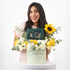 Smiling woman holds vibrant yellow and white floral gift box with "Get Well Soon" message.