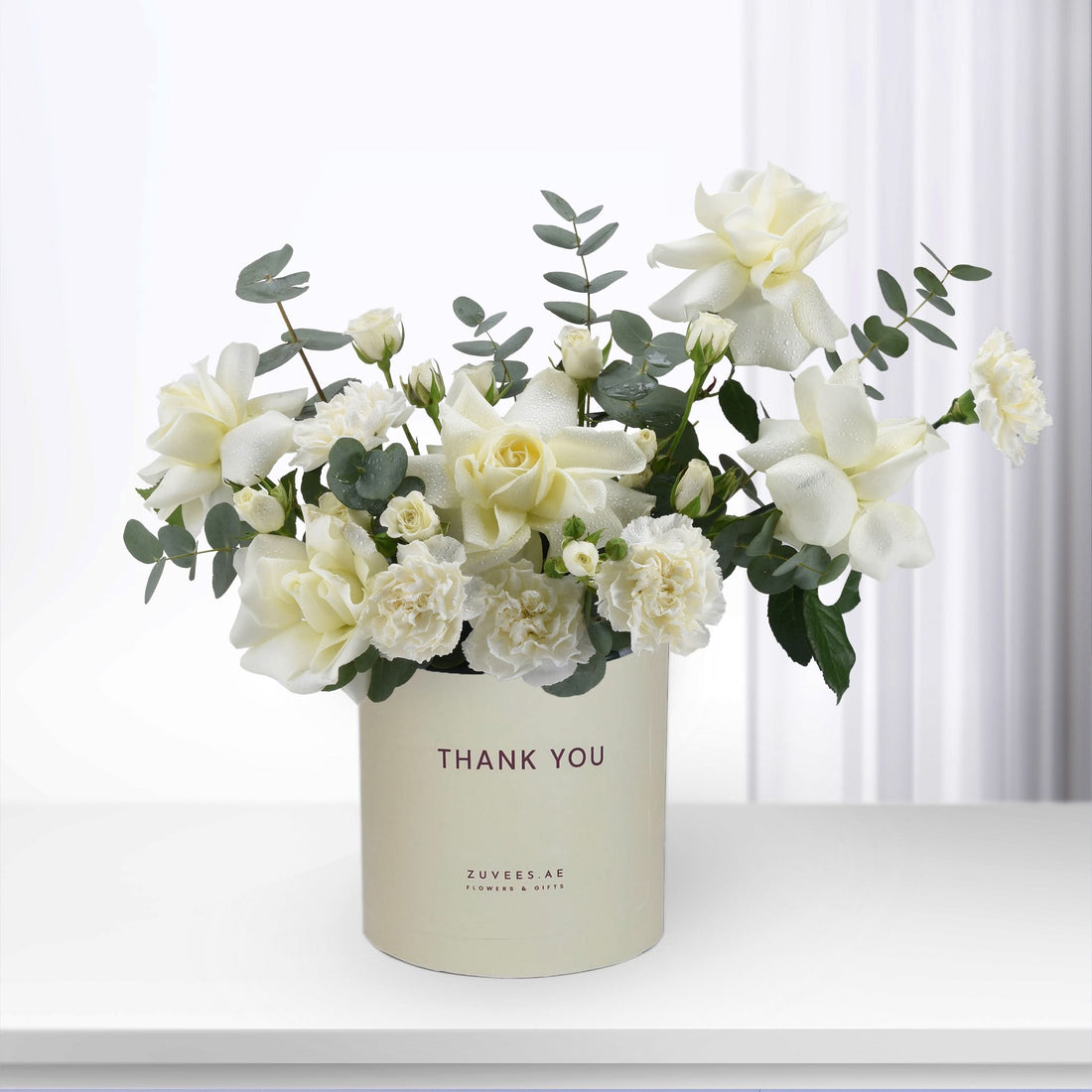 Elegant white rose and carnation bouquet in "Thank You" branded cream cylinder.