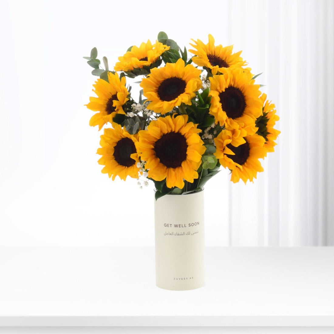 Vibrant sunflowers in cream vase with "Get Well Soon" message.