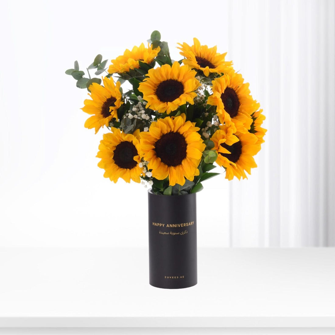 Vibrant sunflowers in matte black vase with "Happy Anniversary" text.