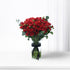 Vibrant red roses in clear vase, accented with black ribbon and eucalyptus.