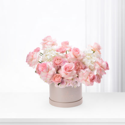 Soft pink roses and hydrangeas bloom elegantly in a blush box.