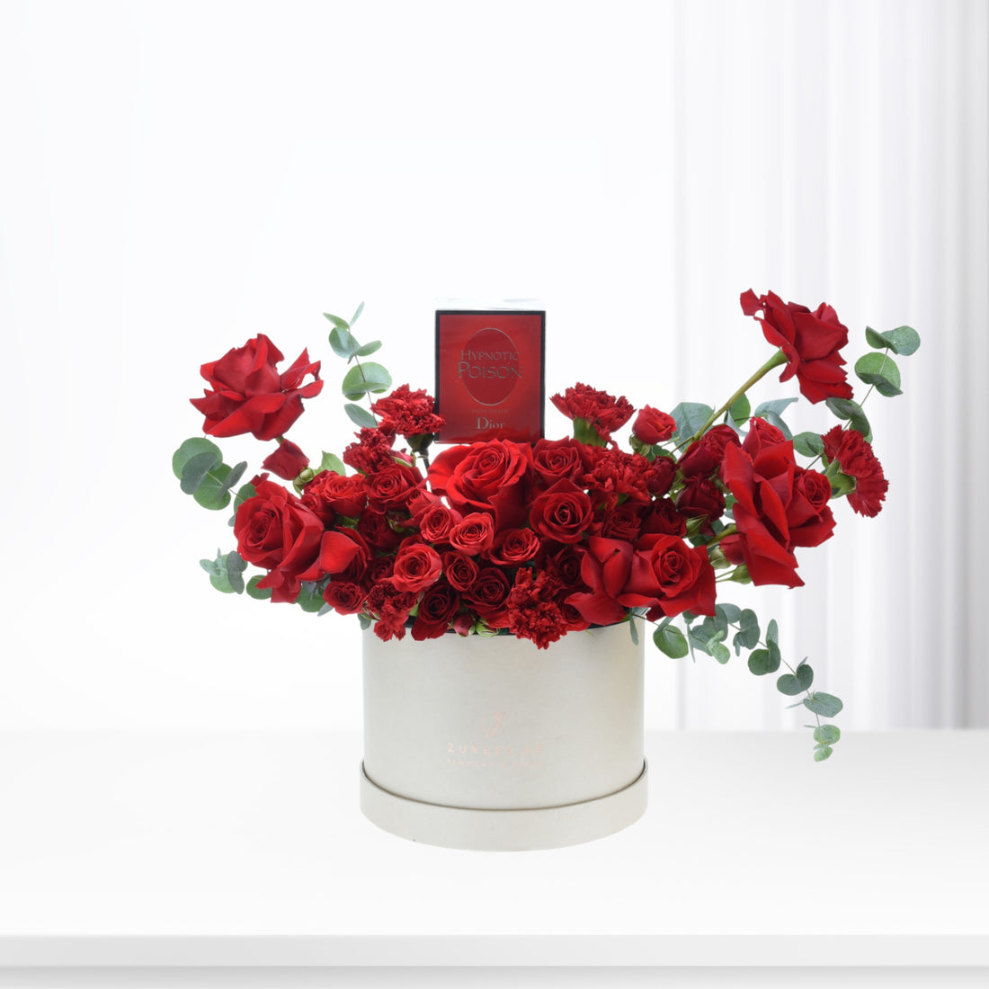 Luxurious red roses, carnations, eucalyptus in white box with Dior Hypnotic Poison perfume.