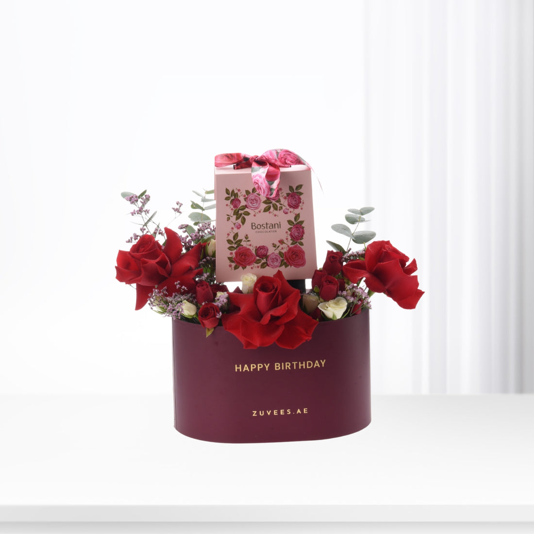 Vibrant red roses and chocolates in burgundy birthday hat.
