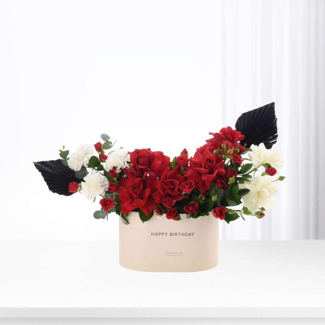 Red roses, white blooms, black accents in cream "Happy Birthday" box, minimalist elegance.