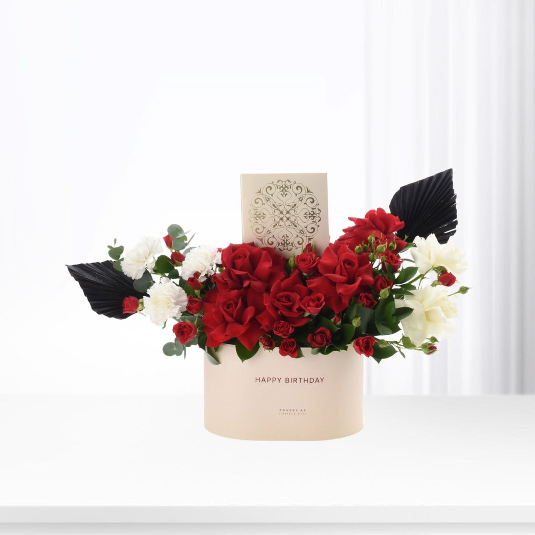 Elegant red and white floral arrangement in beige box with "Happy Birthday" text.