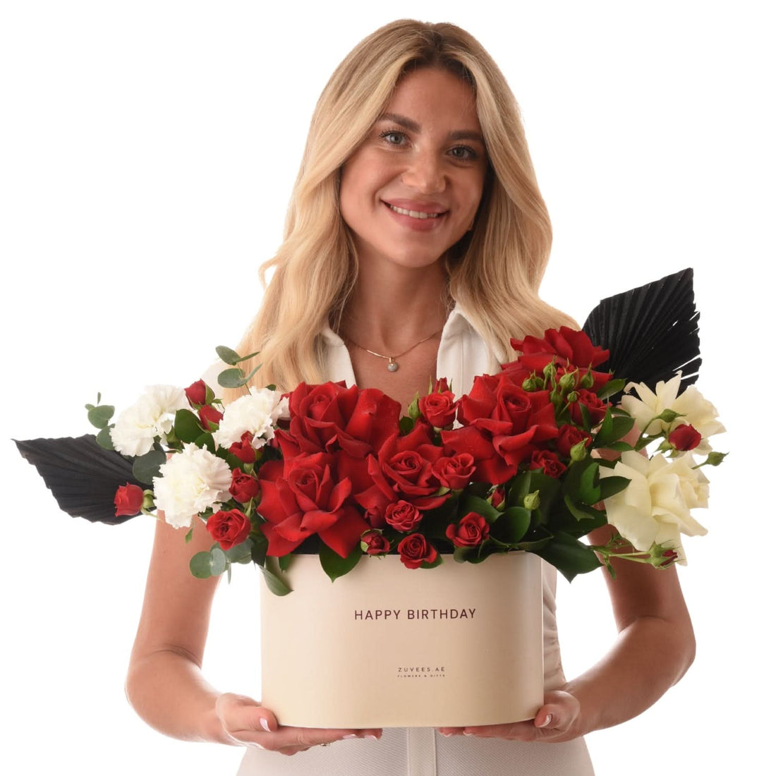 Woman holds elegant birthday flower box with red roses and white blooms.