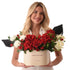 Woman holds elegant birthday flower box with red roses and white blooms.