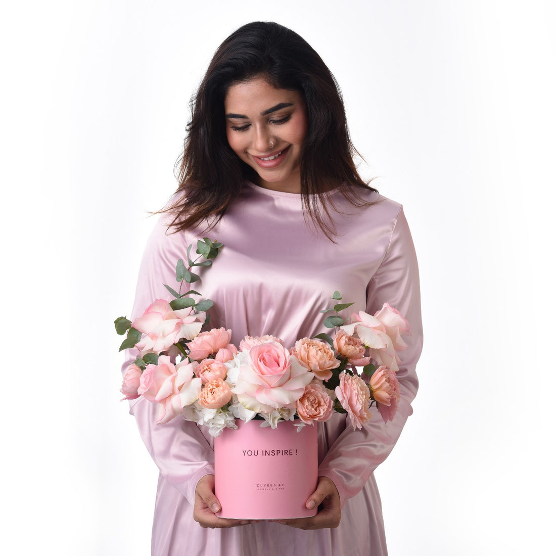 Pink roses in pastel box, woman smiles warmly, elegant gift presentation.
