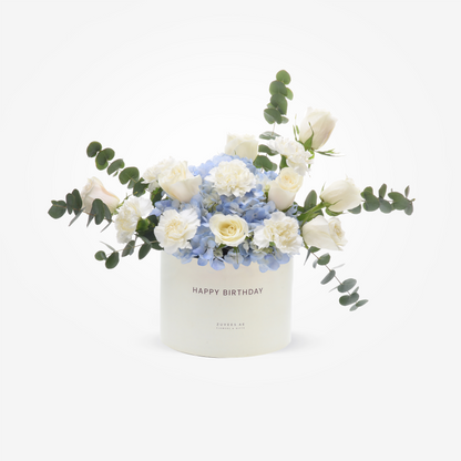 Elegant white rose and hydrangea bouquet in a "Happy Birthday" cylinder, accented with eucalyptus.