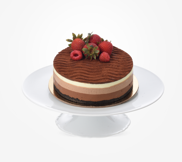 Rich chocolate mousse cake with fresh strawberries and raspberries on white pedestal.