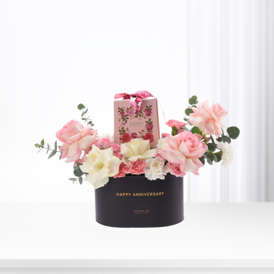 Elegant black anniversary box with pink roses, white blooms, and chocolate gift.