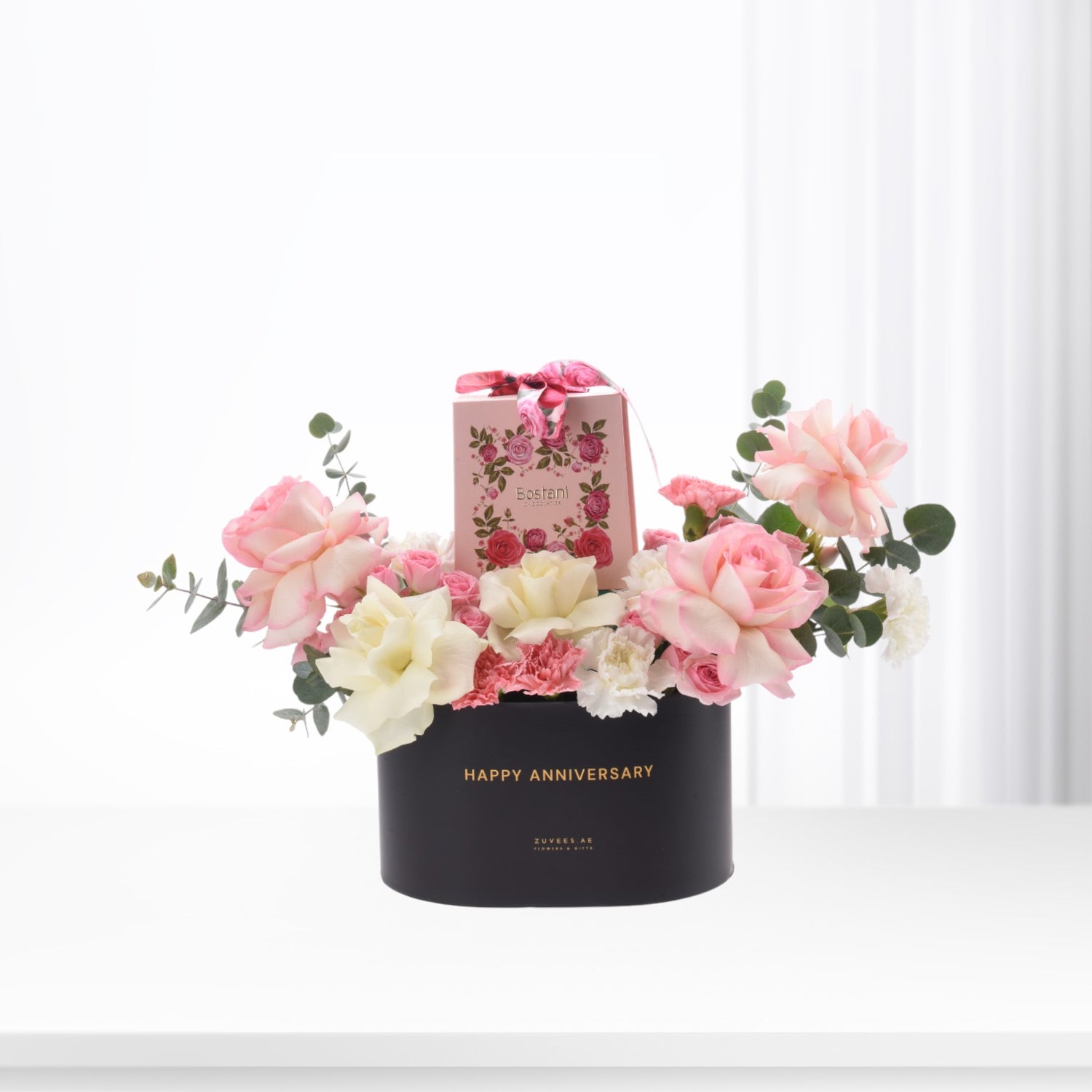Elegant black anniversary box with pink roses, white blooms, and chocolate gift.