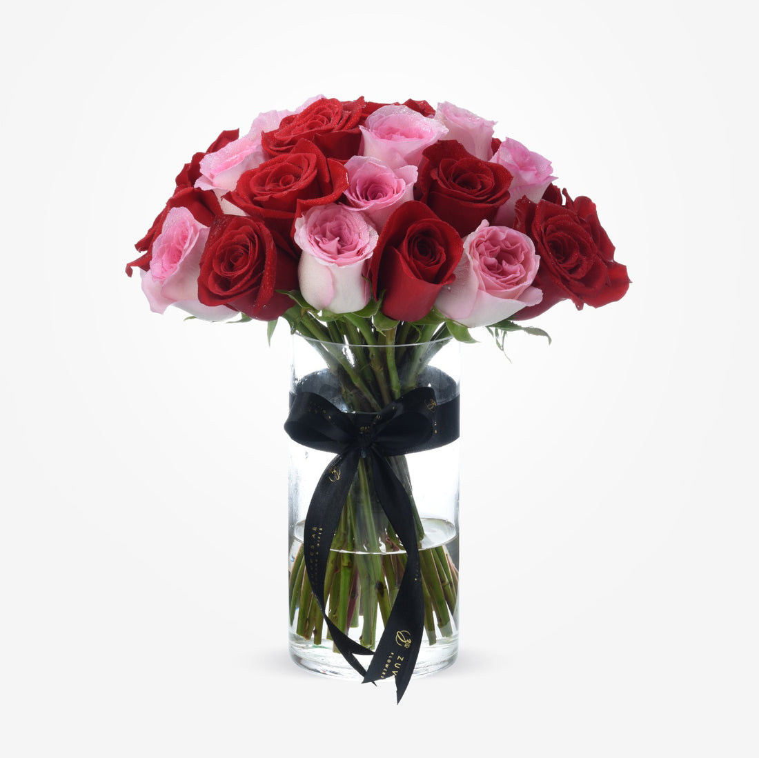 Vibrant red and pink roses in clear vase, elegantly tied with black ribbon.