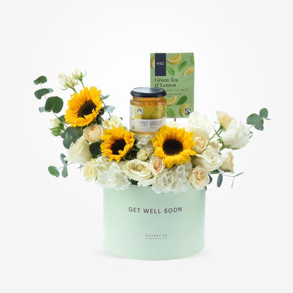 Pastel green box holds sunflowers, white roses, and M&amp;S tea/marmalade.