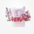 Pink floral baby gift basket with plush toys and bottles.