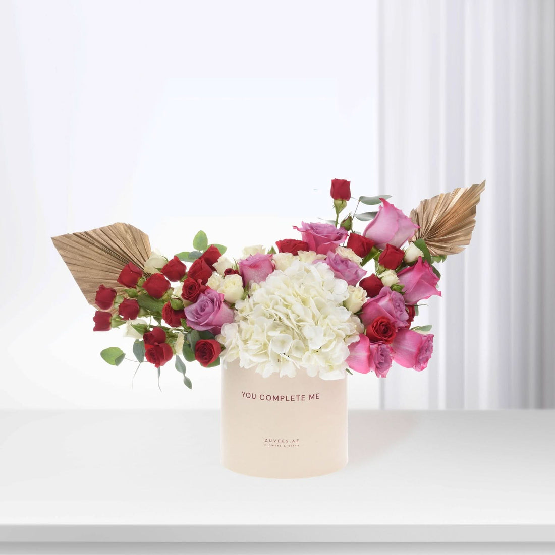 Elegant floral arrangement in blush box with "You Complete Me" message.