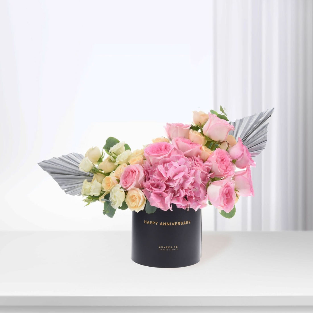 Elegant pink roses and hydrangeas in black box with "Happy Anniversary" gold text.